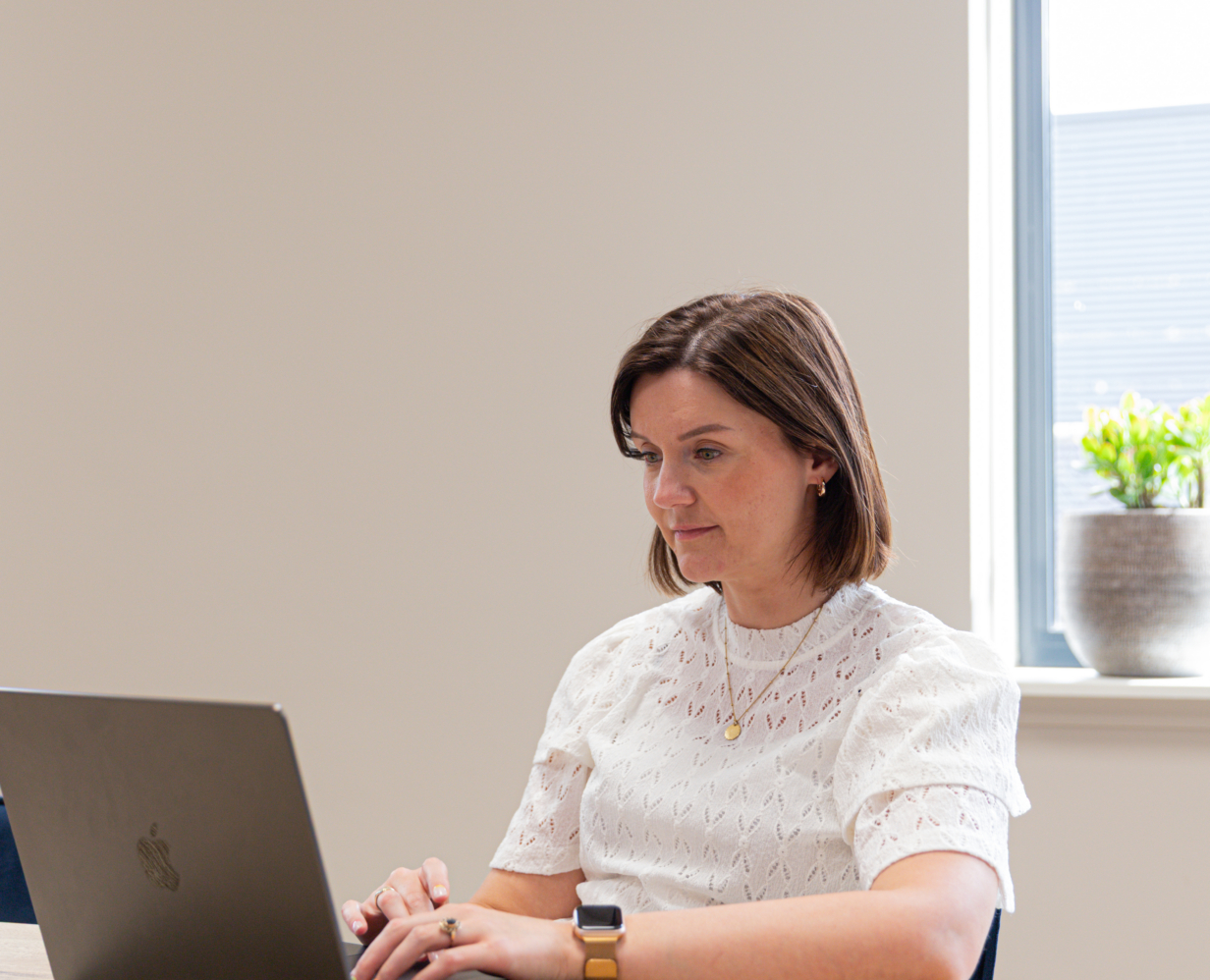 Kicky, content marketeer bij Booosters, zit aan een bureau en is aan het werk op haar laptop.