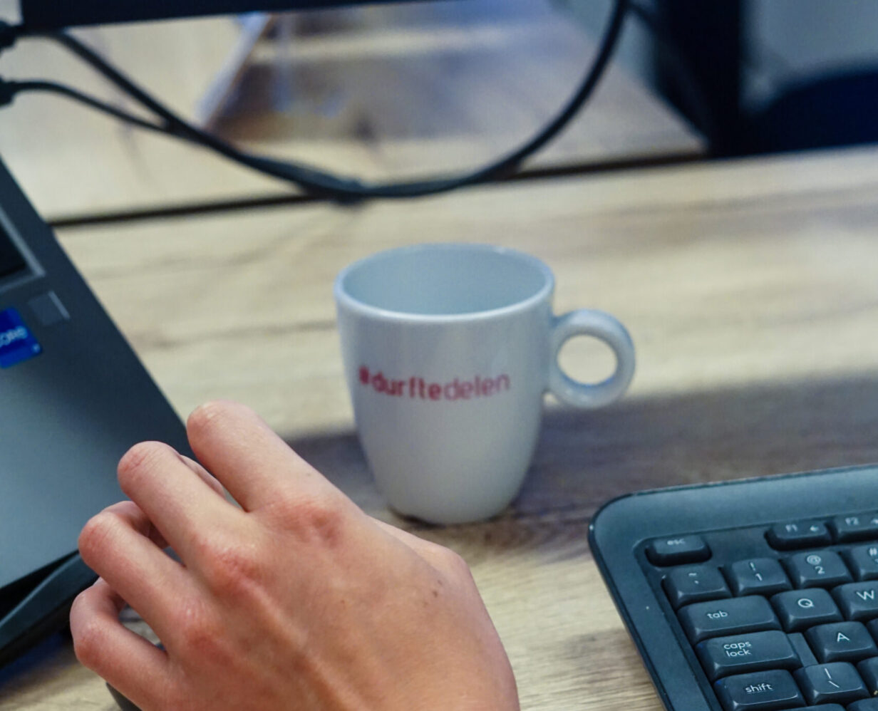 Koffiekopje met Booosters-motto: Durf te delen staat op het bureau van onze online marketeers.