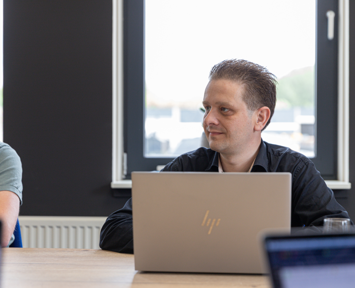 Data & AI specialist Arthur dit aan een vergadertafel met z'n laptop voor zich