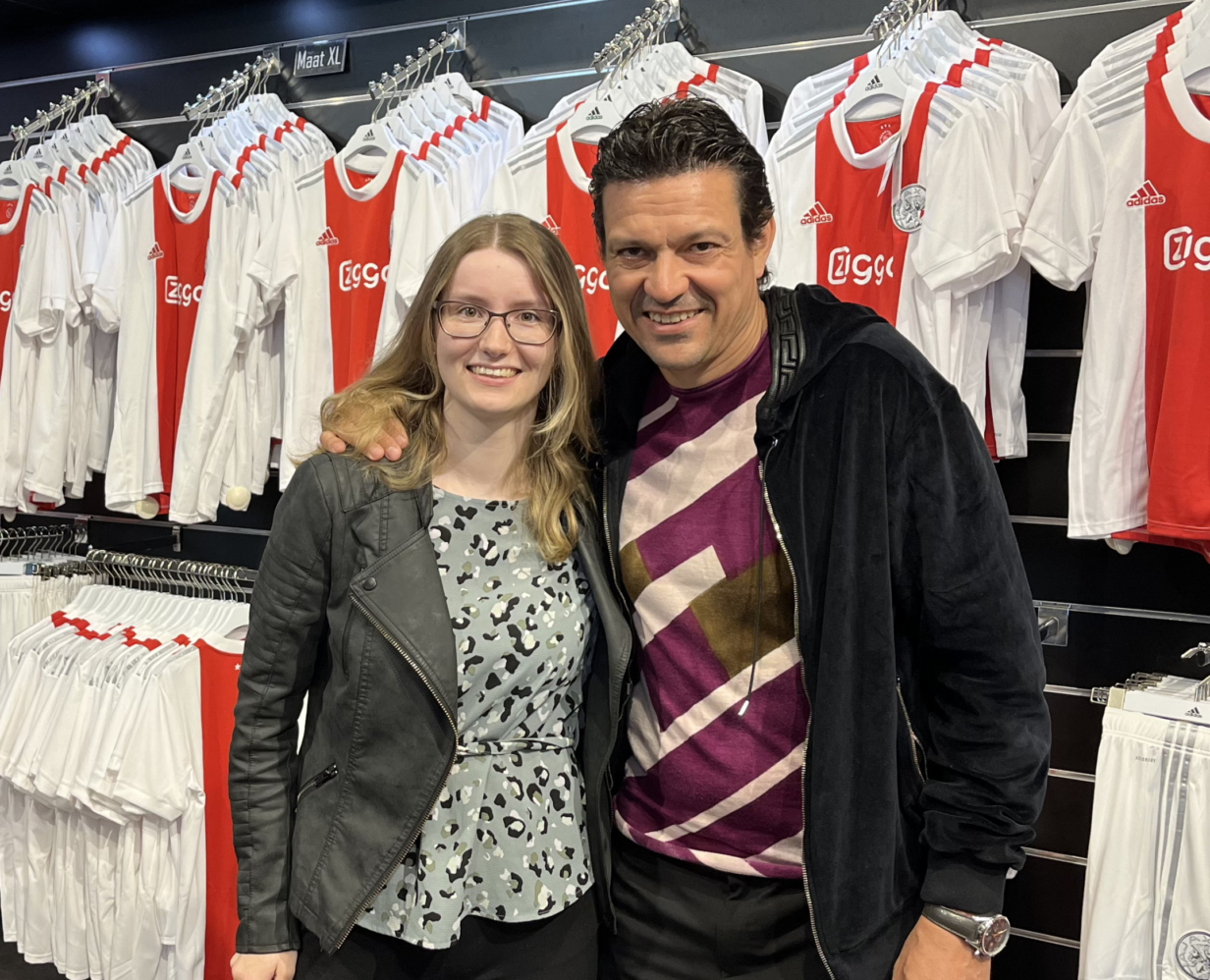 Content marketeer Jamie de Vries staat naast Jari Litmanen in de Ajax fanshop in de Arena