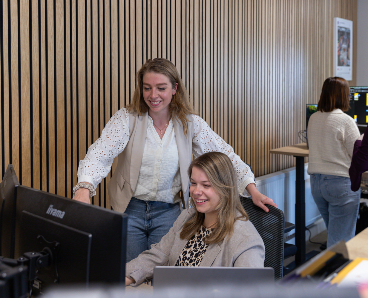 Content marketeers Kim en Anna overleggen achter de laptop