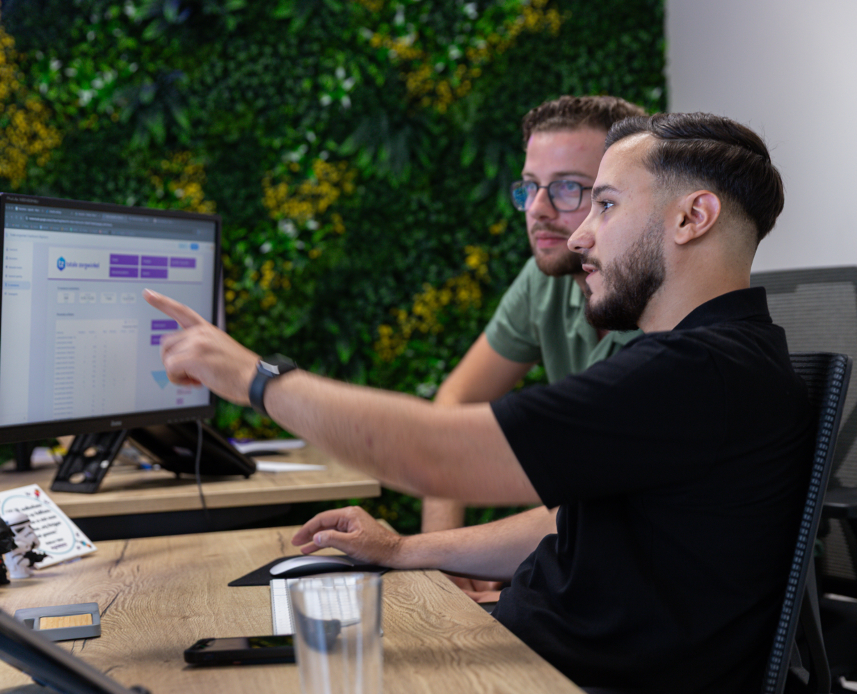 Online marketeers Talha en Timo kijken samen naar een scherm met data