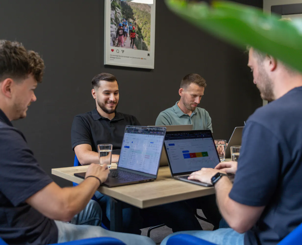 Damian, Jan, Talha en Maurice zitten aan een bureau te werken