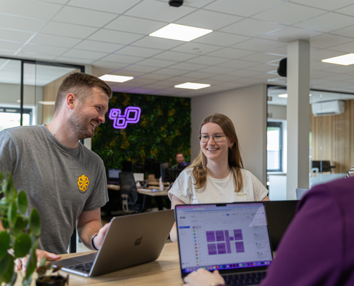Online marketeer Damian die samen met content marketeer Jamie en andere collega's aan het overleggen is.