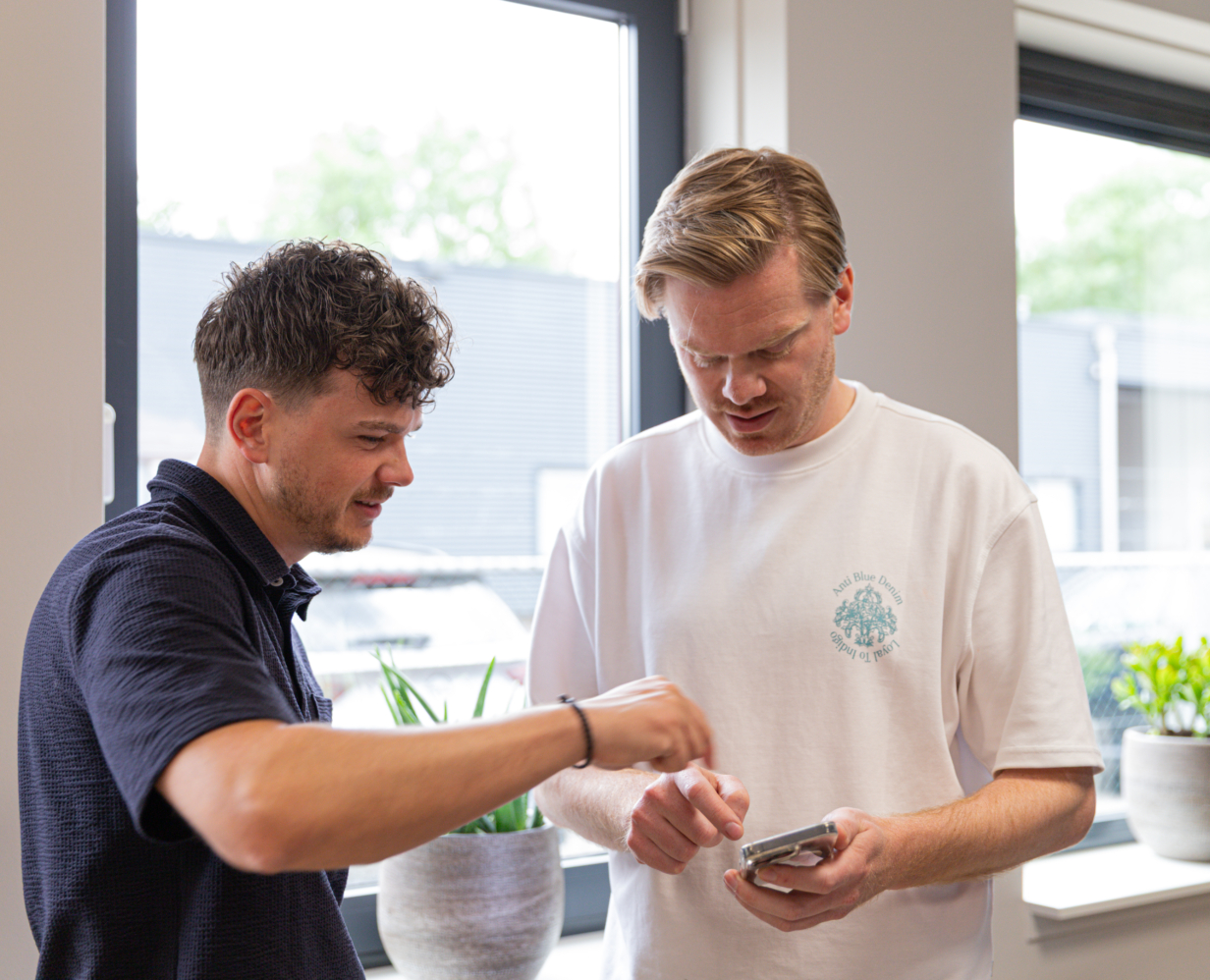 Online marketing adviseurs jan en Gijs kijken samen naar een telefoon
