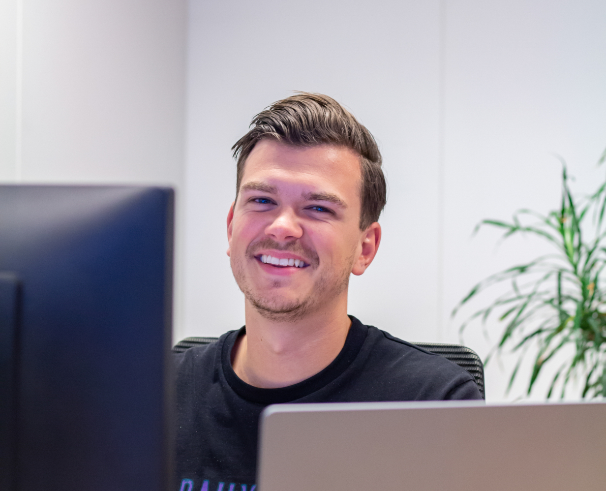 Online marketing adviseur Jan zit aan zijn bureau te werken en kijkt naar de camera